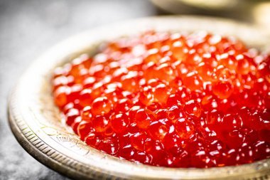 Red caviar in the bowl. On a rustic background. High quality photo