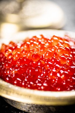 Red caviar in the bowl. On a rustic background. High quality photo