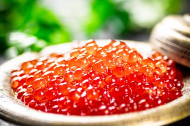 Full bowl of red caviar on the table. On a black background. High quality photo