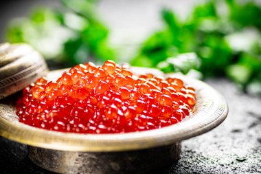 Full bowl of red caviar on the table. On a black background. High quality photo