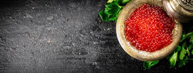 Full bowl of red caviar on the table. On a black background. High quality photo