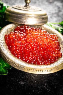 Full bowl of red caviar on the table. On a black background. High quality photo