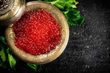 Full bowl of red caviar on the table. On a black background. High quality photo