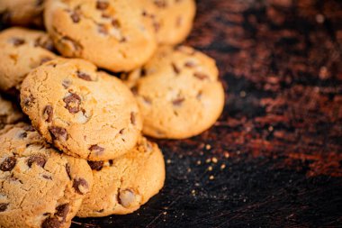 Cookies with pieces of milk chocolate on the table. On a rustic dark background. High quality photo