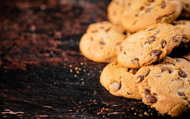 Cookies with pieces of milk chocolate on the table. On a rustic dark background. High quality photo