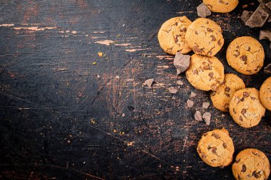 Cookies with pieces of milk chocolate on the table. On a rustic dark background. High quality photo