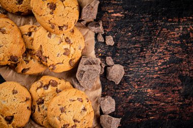 Cookies with pieces of milk chocolate on the table. On a rustic dark background. High quality photo