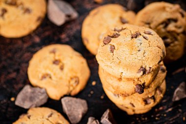 Cookies with pieces of milk chocolate on the table. On a rustic dark background. High quality photo