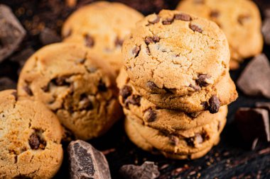 Cookies with pieces of milk chocolate on the table. On a rustic dark background. High quality photo