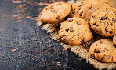 Cookies with pieces of milk chocolate on the table. On a rustic dark background. High quality photo