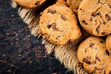 Cookies with pieces of milk chocolate on the table. On a rustic dark background. High quality photo