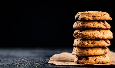 A pile of milk chocolate cookies. On a black background. High quality photo