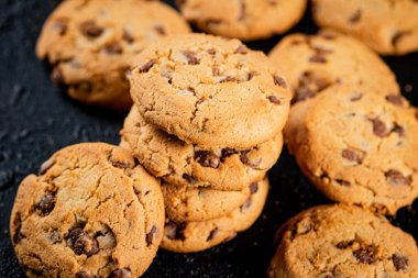 A pile of milk chocolate cookies. On a black background. High quality photo