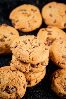 A pile of milk chocolate cookies. On a black background. High quality photo