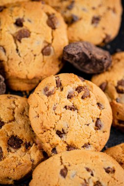 Cookies with pieces of milk chocolate on the table. On a rustic dark background. High quality photo