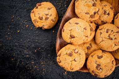 Delicious cookies with pieces of milk chocolate on a plate. On a black background. High quality photo