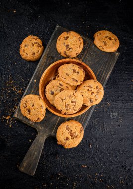 Cookies with milk chocolate on a cutting board. On a black background. High quality photo