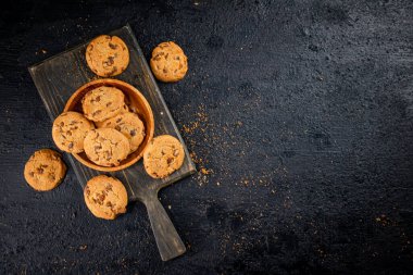 Cookies with milk chocolate on a cutting board. On a black background. High quality photo