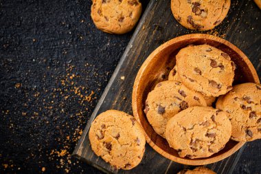 Cookies with milk chocolate on a cutting board. On a black background. High quality photo