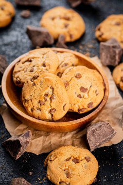 Delicious cookies with pieces of milk chocolate on a plate. On a black background. High quality photo