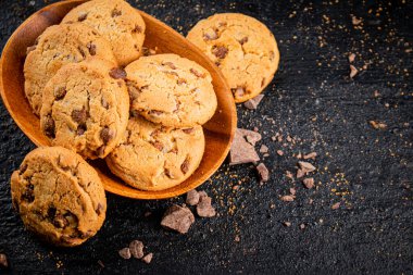 Wooden plate with cookies and pieces of milk chocolate. On a black background. High quality photo