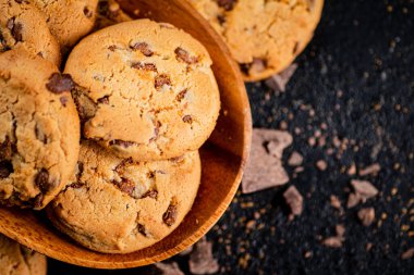 Wooden plate with cookies and pieces of milk chocolate. On a black background. High quality photo