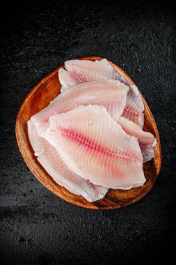 Fresh fish fillet on a wooden plate. On a black background. High quality photo