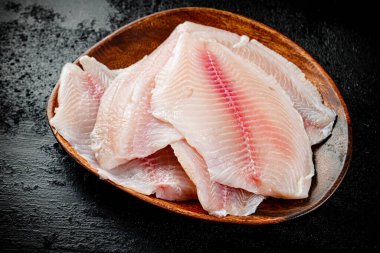 Fresh fish fillet on a wooden plate. On a black background. High quality photo