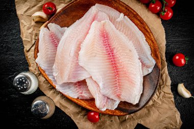 Fresh fish fillet on a wooden plate. On a black background. High quality photo