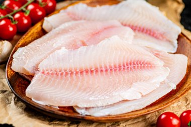 Raw fish fillet on a plate with a branch of tomatoes. Macro background. High quality photo