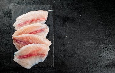 Raw fish fillet on a stone board. On a black background. High quality photo