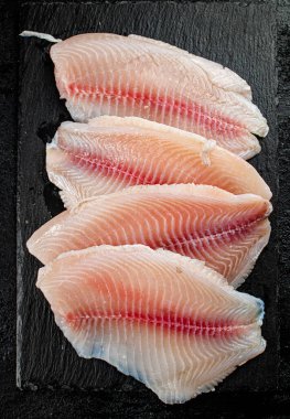 Raw fish fillet on a stone board. On a black background. High quality photo