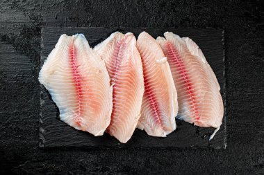 Raw fish fillet on a stone board. On a black background. High quality photo