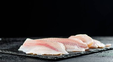 Uncooked fish fillet on the table. On a black background. High quality photo