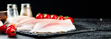 Raw fish fillet with tomatoes and spices. On a black background. High quality photo