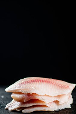 Uncooked fish fillet on the table. On a black background. High quality photo