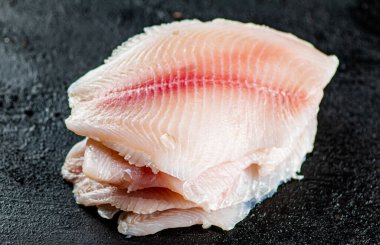 Uncooked fish fillet on the table. On a black background. High quality photo