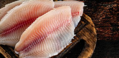 Raw fish fillet on a wooden cutting board. Against a dark background. High quality photo