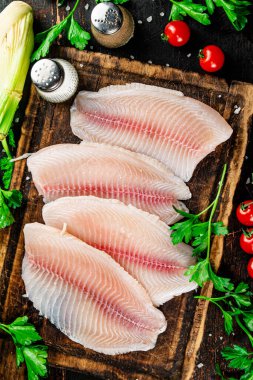 Raw fish fillet with greens on a cutting board. Against a dark background. High quality photo
