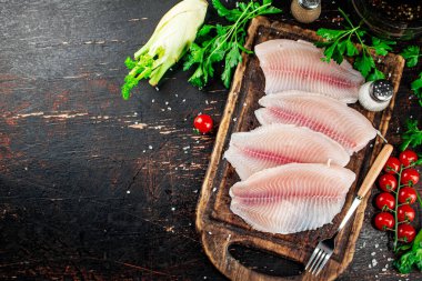 Raw fish fillet with tomatoes and herbs. Against a dark background. High quality photo