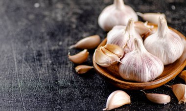 Fresh garlic on a wooden plate. On a black background. High quality photo