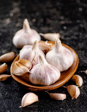Fresh garlic on a wooden plate. On a black background. High quality photo