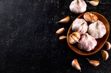 Fresh garlic on a wooden plate. On a black background. High quality photo