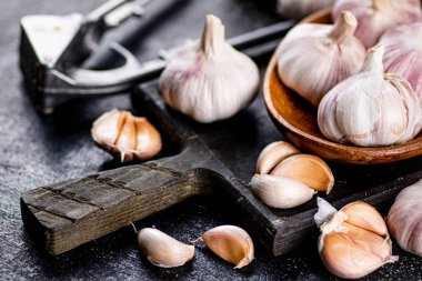 Garlic on a wooden plate on a cutting board. On a black background. High quality photo