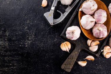 Garlic on a wooden plate on a cutting board. On a black background. High quality photo