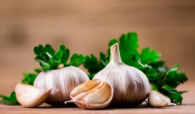 Cloves of fresh garlic with parsley. On a wooden background. High quality photo