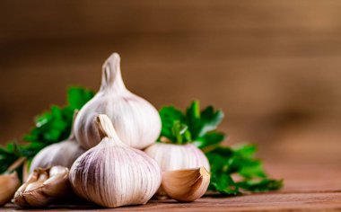 Cloves of fresh garlic with parsley. On a wooden background. High quality photo