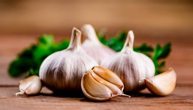 Cloves of fresh garlic with parsley. On a wooden background. High quality photo