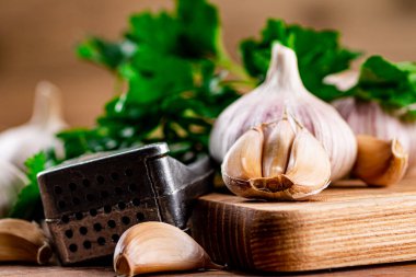 Garlic with parsley on a wooden cutting board. On a wooden background. High quality photo