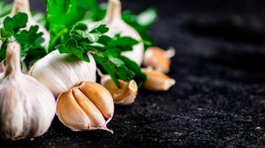 Fragrant garlic with parsley on the table. On a black background. High quality photo